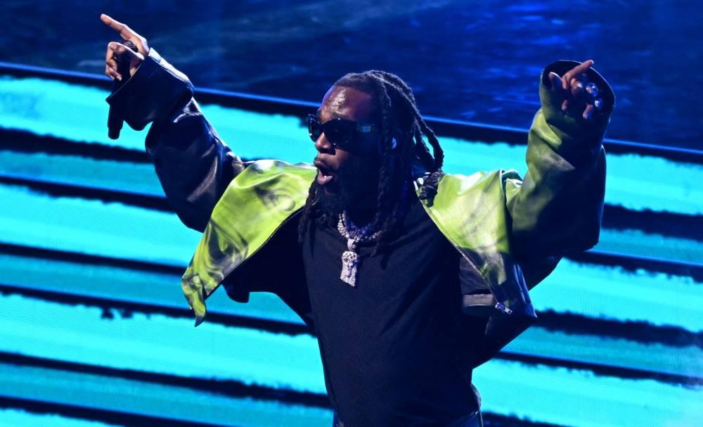 Burna Boy spraying dollar notes on Adewale Ayuba during a live Fuji music performance